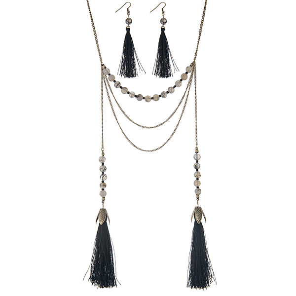 Burnished gold tone layering necklace set displaying black and white beads with two 3 1/2" fabric tassels. Approximately 28" in length.