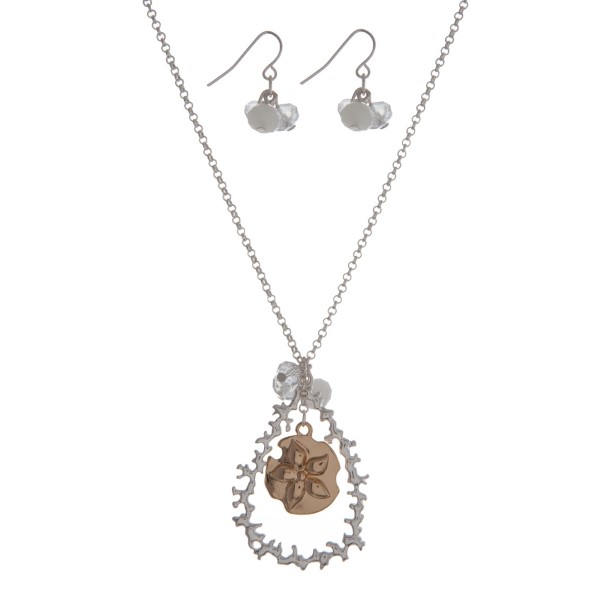 Silver tone necklace set with a two tone sand dollar and coral reef teardrop pendant, accented with a white opal bead. Approximately 18" in length. 