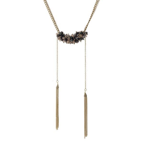 Burnished gold tone necklace with gray and beige beads and two chain tassels. Necklace is approximately 20" in length and tassels are approximately 5" in length. 