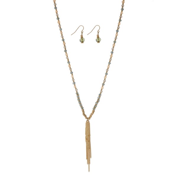 Dainty gold tone necklace set with green beads and a chain tassel. Approximately 32" in length. 