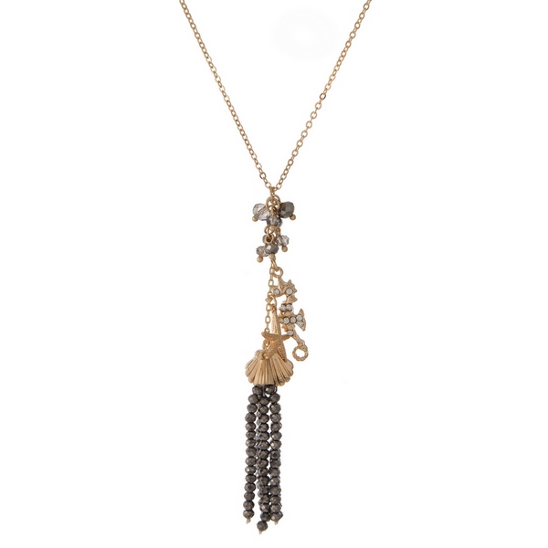 Gold tone necklace featuring a hematite beaded tassel pendant, accented with seashell, starfish, and seahorse charms. Approximately 20" in length. 