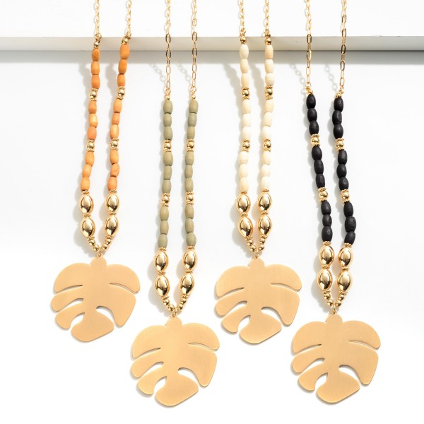 Long Gold tone chain with gold beads and Black colored wood beads featuring a large palm leaf pendant 

-Approximately  34 inches long 
-Approximately 2 inch extender
-Pendant Approximately 1.5 inches long 
