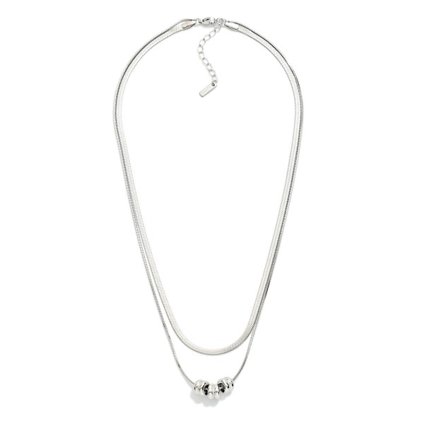 Layered Herringbone Chain Link Necklace Feating Metal Tone Beaded Disks 

- Stainless Steel 
- Approximately 16.5" L
- Extender 2" L 