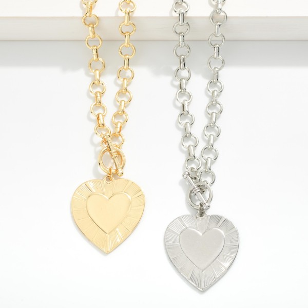Metal Tone Circle Chain Link Necklace Featuring Heart Pendant & Toggle Clasp 

- Approximately 18" L 