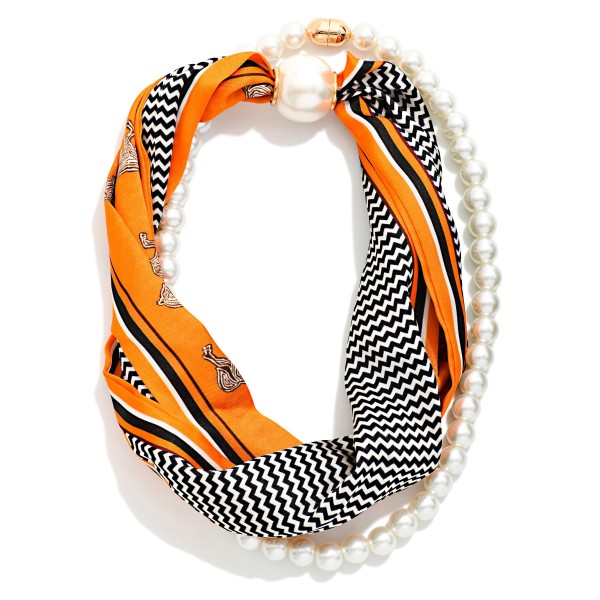 Satin Scarf and Pearl Necklace that twists a silky scarf in bold chevron and stripe prints together with a strand of faux pearls, finished with an oversized pearl closure. The blend of soft fabric and classic pearls creates an effortless, Parisian inspired look in seconds. Wear it with a crew neck sweater, button down, or simple dress to instantly finish an outfit. A unique, giftable accessory that stands out on the display and appeals to shoppers who love an easy, styled look.