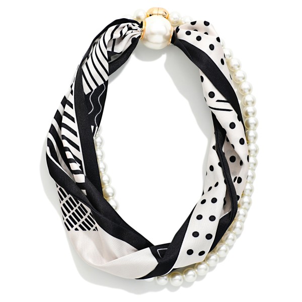 Satin Scarf and Pearl Necklace that twists a silky scarf in mixed geometric and polka dot prints together with a strand of faux pearls, finished with an oversized pearl closure. The blend of soft fabric and classic pearls creates an effortless, Parisian inspired look in seconds. Wear it with a crew neck sweater, button down, or simple dress to instantly finish an outfit. A unique, giftable accessory that stands out on the display and appeals to shoppers who love an easy, styled look.