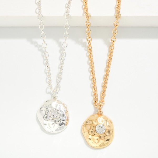 Hammered Disc Pendant Necklace with a polished coin charm set with a sparkling crystal accent on a classic rolo chain. The organic hammered texture catches the light from every angle, and the extender makes the length easy to adjust. A simple everyday layering piece that works for gifting, workwear and weekends. An easy price point that turns browsers into buyers at the jewelry wall.