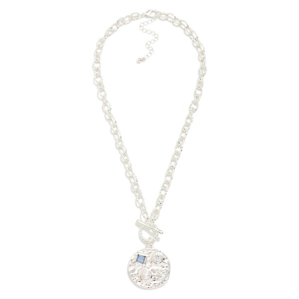 Toggle Medallion Necklace with a hammered coin pendant studded with crystal and stone accents, hung from a front toggle on a textured rolo chain. The organic hammered finish feels artisan and works with everything from denim to dresses, with an extender for easy sizing. A versatile everyday piece for gifting, travel and weekend style. Coin and toggle details are trending, and this one hits both at an easy price point.