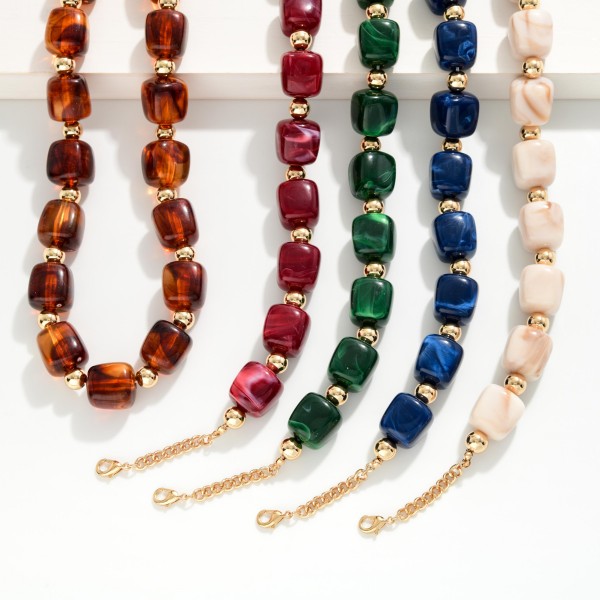 Chunky Resin Bead Necklace strung with polished barrel shaped beads spaced by small metal accents, finished with an adjustable chain extender. The marbled resin finish has the rich look of stone without the weight, so it sits comfortably at the collarbone all day. Pair it with crew neck sweaters, button downs, or simple dresses. Statement resin pieces are a strong seller for fall, and this style offers an elevated look at an easy price point.