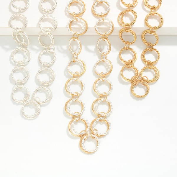 Textured Circle Link Necklace made from interlocking round rings with a twisted rope texture that catches the light. The open circle design feels modern and airy while still making a confident statement at the collarbone. Finished with a lobster clasp and extender chain. A fresh alternative to classic chains that pairs easily with crew necks, V necks, and button down shirts for everyday styling.