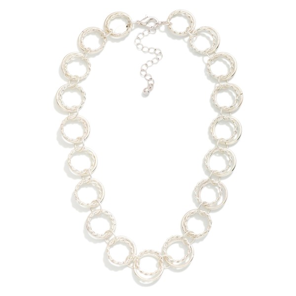 Textured Circle Link Necklace made from interlocking round rings with a twisted rope texture that catches the light. The open circle design feels modern and airy while still making a confident statement at the collarbone. Finished with a lobster clasp and extender chain. A fresh alternative to classic chains that pairs easily with crew necks, V necks, and button down shirts for everyday styling.