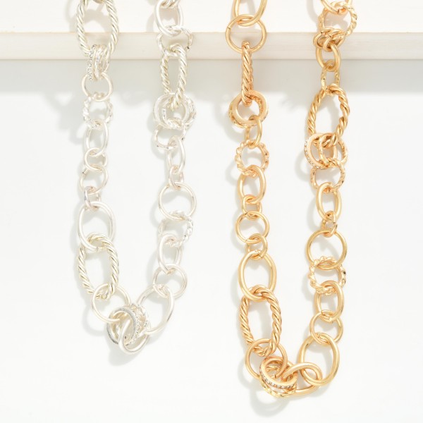 Mixed Link Chain Necklace combining smooth and textured oval links with subtle sparkling accents for added dimension. The worn metal finish gives it a relaxed, vintage feel that layers well with pendants or stands alone as a polished collar piece. Lobster clasp closure with an extender chain. A versatile chain necklace that sells across ages and works with everything from denim to dresses.