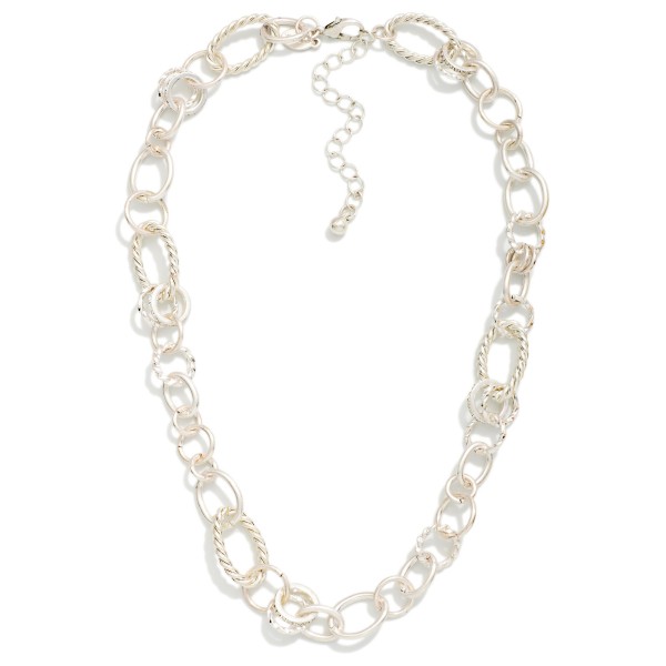 Mixed Link Chain Necklace combining smooth and textured oval links with subtle sparkling accents for added dimension. The worn metal finish gives it a relaxed, vintage feel that layers well with pendants or stands alone as a polished collar piece. Lobster clasp closure with an extender chain. A versatile chain necklace that sells across ages and works with everything from denim to dresses.
