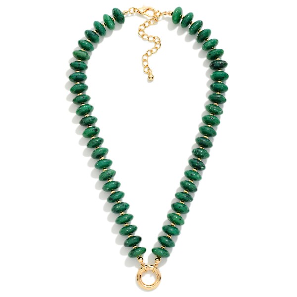 Rondelle Bead Necklace lined with glossy marbled beads that taper into a V shape and finish with a polished open ring accent at the center. The streamlined design sits beautifully at the neckline and layers easily with chains and pendants. Wear it with open collars, V neck tops, and simple knits for an instant pop of texture. A trend right beaded style at an approachable price, it is an easy one to stock deep for the season.