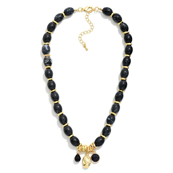Polished Oval Bead Necklace with a cluster of mixed charms at the center, including a smooth stone drop and a hammered metal disc. The glossy beads have a natural, stone inspired finish that adds warmth to fall and winter outfits. A lobster clasp and extender chain make sizing simple. Charm accents give this style a personal, collected feel that shoppers love, making it an easy gift and a dependable seller.
