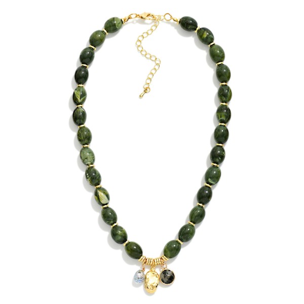 Polished Oval Bead Necklace with a cluster of mixed charms at the center, including a smooth stone drop and a hammered metal disc. The glossy beads have a natural, stone inspired finish that adds warmth to fall and winter outfits. A lobster clasp and extender chain make sizing simple. Charm accents give this style a personal, collected feel that shoppers love, making it an easy gift and a dependable seller.