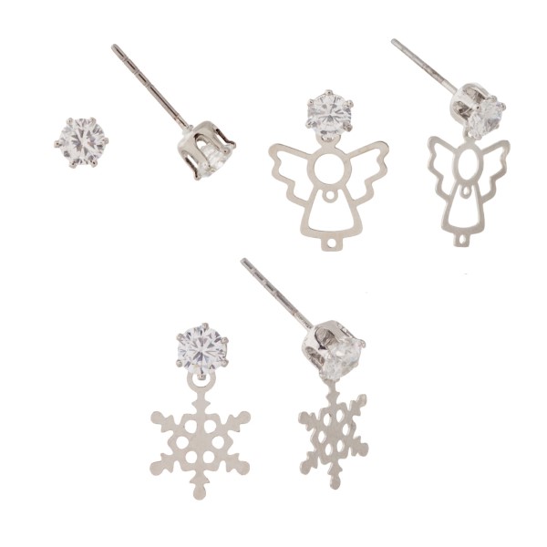 Set of three silver tone post style earrings with a cubic zirconia stud, a stud with a dangling snowflake, and a stud with a dangling angel.