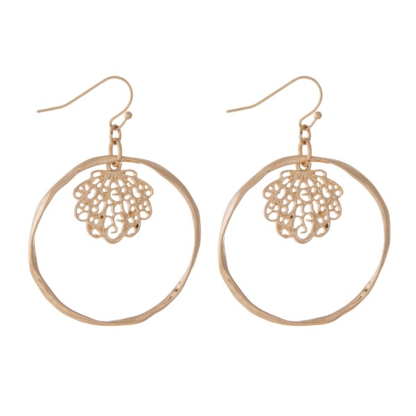 Gold tone fishhook earrings with a hammered circle and a filigree seashell. Approximately 1.25" in diameter. 
