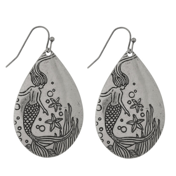 Burnished metal fishhook earrings stamped with a mermaid. Approximately 2" in length. 