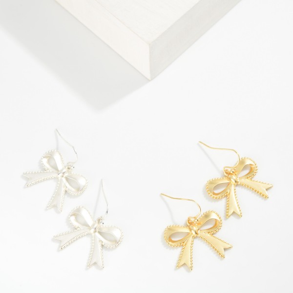 Metal Tone Bow Drop Earrings Featuring Studded Edge Detail 

- Approximately 1" L