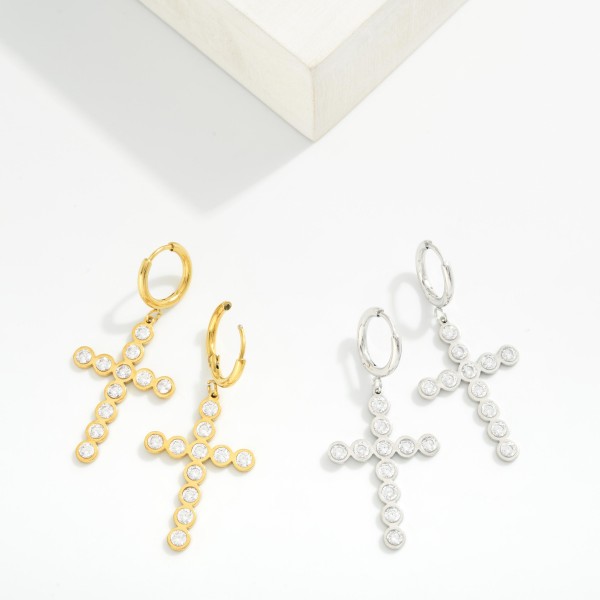 Metal Tone Huggie Hoop Earrings Featuring Rhinestone Studded Cross Dangle 

- Stainless Steel
- Water Resistant
- Approximately 2" L