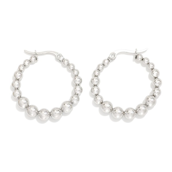 Metal Tone Beaded Huggie Hoop Drop Earring 

- Approximately 1" D 
- Stainless Steel 
- Water Resistant 
- Hypoallergenic