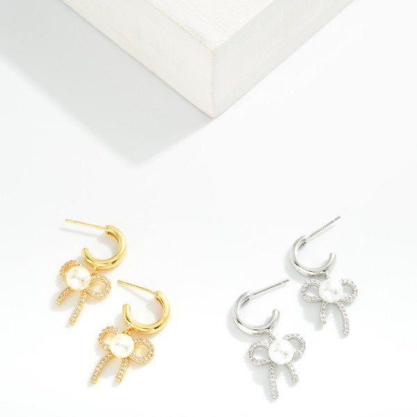  Metal Tone Hoop Earrings Featuring Cubic Zirconia & Pearl Bow Dangle Detail 

- Gold Dipped 
- Approximately 1" L