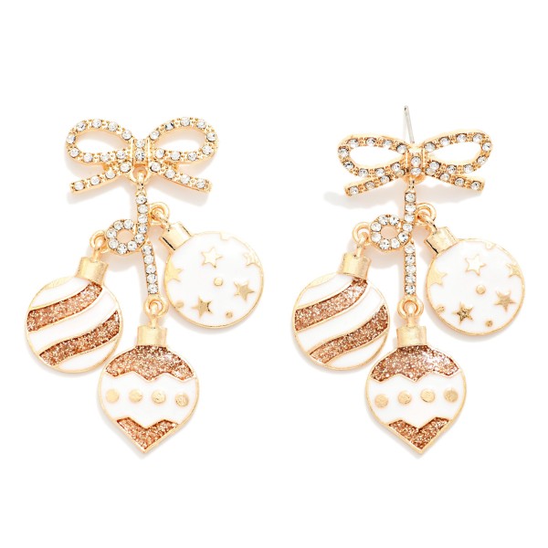 Christmas Ornament Cluster Drop Earrings featuring a sparkling rhinestone bow post with three dangling enamel ornaments, each finished with glitter stripes, stars, and dotted details. The mix of shapes and textures gives these a vintage inspired holiday look that moves and catches the light with every turn. Perfect for Christmas parties, tree trimming nights, and festive family photos. Bows and sparkle are two of the season's biggest trends, so expect these to sell through fast.