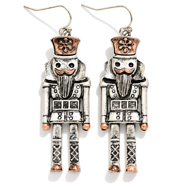 Antiqued Metal Nutcracker Drop Earrings featuring a detailed toy soldier nutcracker with a tall crown hat, carved beard, button coat, and lattice boots, all in a burnished, vintage inspired metal finish. The tall, slender shape hangs gracefully from lightweight fishhook wires. A favorite for Nutcracker ballet season, dance teachers, collectors, and holiday parties. Classic and timeless, nutcracker jewelry sells every Christmas and makes an easy gift.