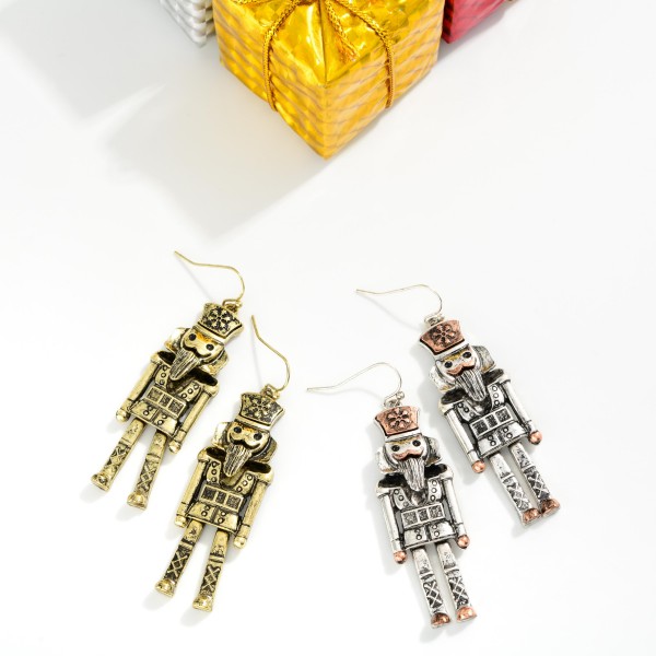 Antiqued Metal Nutcracker Drop Earrings featuring a detailed toy soldier nutcracker with a tall crown hat, carved beard, button coat, and lattice boots, all in a burnished, vintage inspired metal finish. The tall, slender shape hangs gracefully from lightweight fishhook wires. A favorite for Nutcracker ballet season, dance teachers, collectors, and holiday parties. Classic and timeless, nutcracker jewelry sells every Christmas and makes an easy gift.