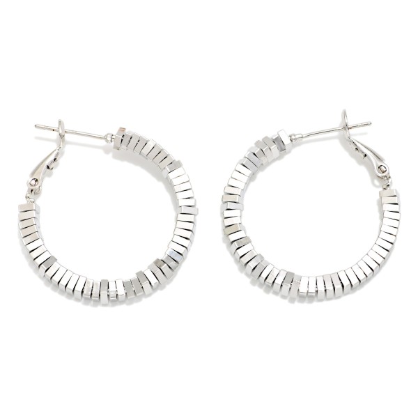 Faceted Disc Bead Hoop Earrings featuring a hoop lined with stacked, angular metal disc beads that create a textured, light catching ridge all the way around. A secure latch back keeps them in place, and the medium size works for everyday wear or a night out. A modern, architectural take on the classic hoop that pairs well with sweaters, denim, and dresses. Textured metal hoops are a strong trend and a great add on for customers who already own the basics.