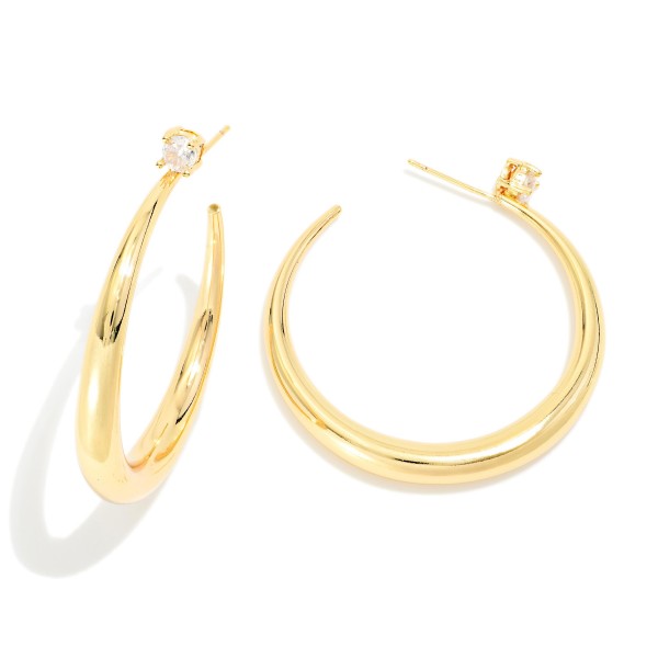 Tapered Open Hoop Earrings with a graduated, sculpted profile that thickens toward the bottom for a modern, polished look. A tiny sparkling stone accents each post for a subtle touch of shine. Easy to dress up or down for work, weekends, and special events. Sleek statement hoops like these are a boutique staple that sells consistently all year.