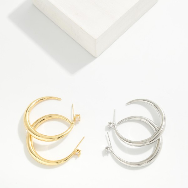 Tapered Open Hoop Earrings with a graduated, sculpted profile that thickens toward the bottom for a modern, polished look. A tiny sparkling stone accents each post for a subtle touch of shine. Easy to dress up or down for work, weekends, and special events. Sleek statement hoops like these are a boutique staple that sells consistently all year.