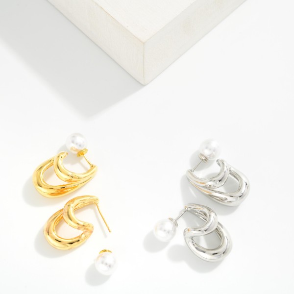 Double Loop Pearl Back Earrings featuring two sculpted, high polish loops that drape below the lobe, finished with a faux pearl ball backing that peeks out behind the ear. The front and back design gives a modern, editorial look from every angle while staying light enough for all day wear. A standout pick for date nights, holiday parties, and fashion forward customers. Statement metals with a pearl twist are trending hard and make a strong impulse sell.