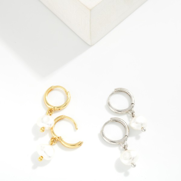 Baroque Pearl Huggie Drop Earrings featuring an organic shaped faux pearl dangling from a polished huggie hoop with a secure hinged closure. The irregular pearl shape gives a modern, artisan feel, while the snug huggie keeps them comfortable from morning meetings to evening plans. A versatile gift for brides, bridesmaids, and anyone who loves classic polish with a twist. Pearl huggies are a top trend, making these an easy, fast turning add on.