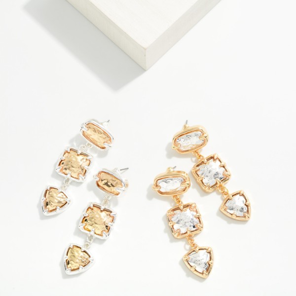 Two Tone Tiered Drop Earrings linking three hammered metal stones, an oval, a square and a shield shape, each held in a contrasting prong setting. The mixed metal finish and stacked shapes give a bold, collected look that still feels lightweight. A standout pick for holiday parties, weddings and dressing up everyday outfits. Mixed metal statement drops are a quick sell for shoppers who want one pair that goes with everything.