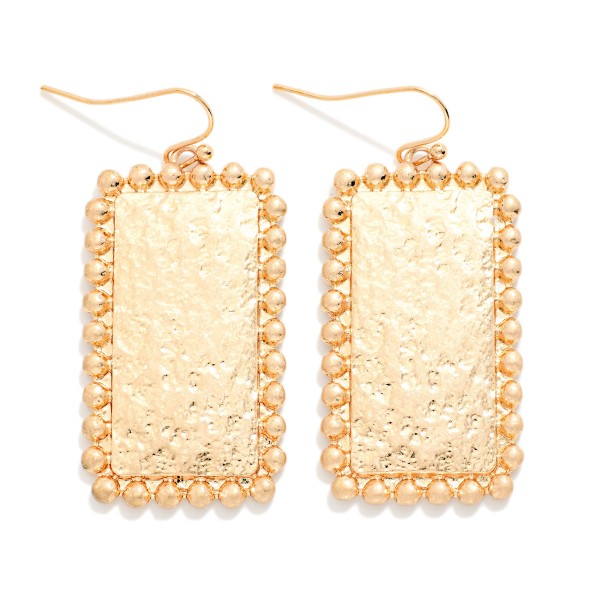 Hammered Rectangle Drop Earrings with a textured metal panel framed by a beaded ball edge on fishhook wires. The shimmer of the hammered surface paired with the dotted trim gives a vintage inspired look that stays light enough for daily wear. Easy to pair with everything from tees to holiday dresses. A dependable metal drop that sells to every age at an easy price.