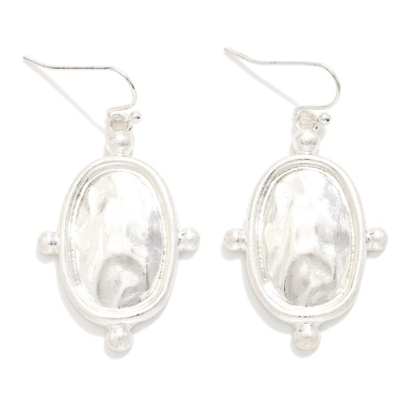 Hammered Oval Drop Earrings with a polished framed medallion accented by tiny ball details on fishhook wires. The hammered center reflects light like a mirror for a vintage inspired look that stays lightweight. An easy everyday style for workwear, church and weekend outfits. A classic metal drop at an easy price point that works for every age.
