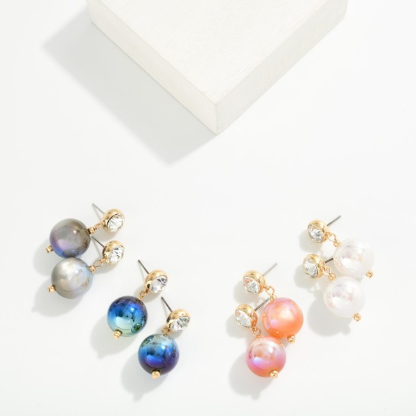 Crystal Stud Pearl Drop Earrings featuring a round bezel set crystal stud with an oversized lustrous pearl bead suspended below. The pairing of sparkle and soft sheen feels polished and elegant without being fussy. Post backs keep them secure and comfortable. Perfect for holiday parties, weddings, and date nights, and a strong gift option offered in several pearl finishes.