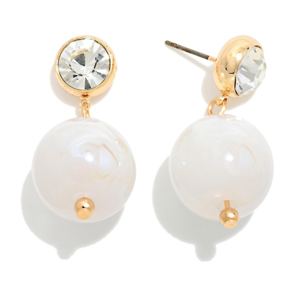 Crystal Stud Pearl Drop Earrings featuring a round bezel set crystal stud with an oversized lustrous pearl bead suspended below. The pairing of sparkle and soft sheen feels polished and elegant without being fussy. Post backs keep them secure and comfortable. Perfect for holiday parties, weddings, and date nights, and a strong gift option offered in several pearl finishes.