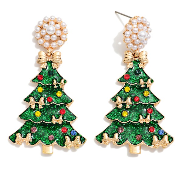 Pearl Cluster Christmas Tree Drop Earrings pairing a pearl cluster post with a glitter enamel tree trimmed in tiny bows and sparkling rhinestone ornaments. The glitter finish catches the light beautifully, while the pearl top adds a dressy touch that elevates any holiday outfit. A standout pick for Christmas parties, church services, and festive photos. Bows, pearls, and sparkle in one design make this an easy, trend right seller for boutique holiday displays.