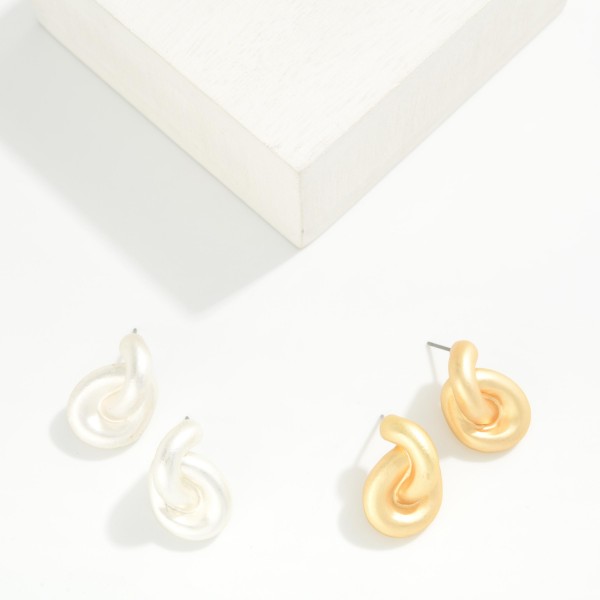 Puffy Twist Stud Earrings with a sculpted, curved knot design in a smooth matte finish. The rounded shape feels soft and modern while still making a bold statement close to the ear. Post backs for secure, comfortable wear. A chunky metal stud that pairs with everything from tees to evening wear, ideal for customers who love bold but easy everyday earrings.