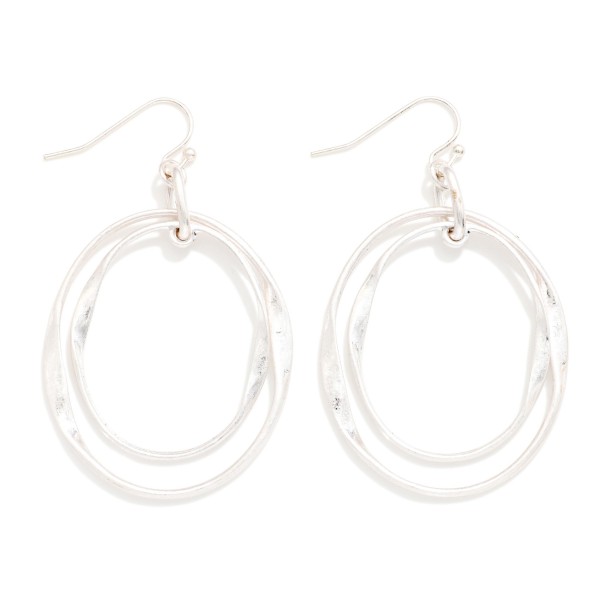 Layered Oval Drop Earrings featuring two overlapping open ovals, one polished and one hammered, hanging from simple fishhook wires. The offset layers create a sculptural, modern look with subtle movement. Light and comfortable for all day wear. A versatile metal earring that pairs with everything in a customer's closet and makes a great entry price point for your earring wall.