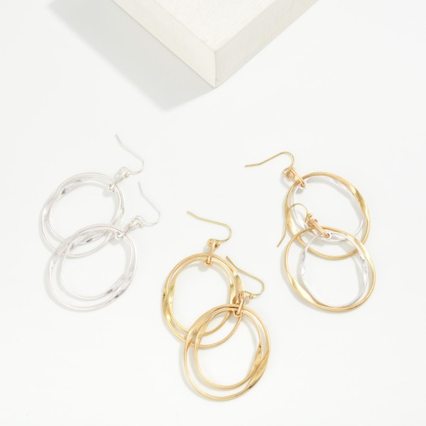 Layered Oval Drop Earrings featuring two overlapping open ovals, one polished and one hammered, hanging from simple fishhook wires. The offset layers create a sculptural, modern look with subtle movement. Light and comfortable for all day wear. A versatile metal earring that pairs with everything in a customer's closet and makes a great entry price point for your earring wall.