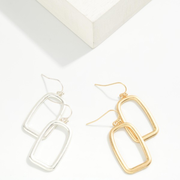 Open Rectangle Drop Earrings with a clean geometric outline in a soft brushed finish, hung from lightweight fishhook wires. The minimal, architectural shape feels modern and pairs with everything from workwear to weekend outfits. Light enough for all day comfort. A simple, on trend earring at an easy price point, perfect for building out an everyday metal earring display.