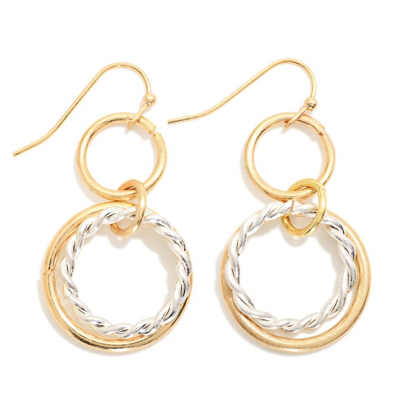 Twisted Rope Double Hoop Drop Earrings featuring a smooth open ring paired with a twisted rope hoop, suspended from a small circle link on fishhook wires. The layered texture adds dimension and movement without extra weight. Easy to wear from day to night. Offered in mixed and single metal finishes, they make a versatile everyday style that sells across a wide range of customers.