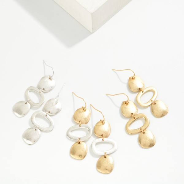 Hammered Geometric Drop Earrings featuring a linear stack of organic shaped discs and an open oval link in a worn metal finish. The artisan inspired texture gives these a collected, boho feel with plenty of movement. Fishhook wires keep them lightweight and comfortable. A statement earring that pairs effortlessly with denim, linen, and flowy dresses for an easy everyday look.