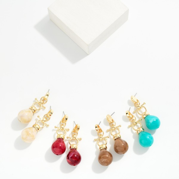 Toggle Drop Earrings pairing a polished metal T bar and ring detail with a glossy marbled resin teardrop. The mix of hardware inspired metal and organic stone look gives a modern, collected feel that dresses up denim and sweaters as easily as evening wear. Lightweight resin keeps them comfortable for hours on post backs. A fresh take on the toggle trend at an impulse friendly price, these are a smart add for boutique earring walls.