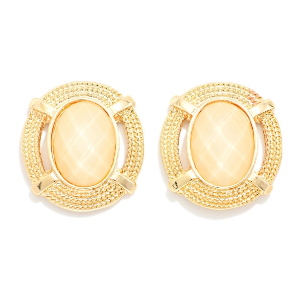 Oval Stone Statement Stud Earrings featuring a faceted oval cabochon set in a textured round metal frame with notched detailing. The decorative border adds vintage charm while the stone delivers rich, polished shine. Lightweight post backs make them comfortable from morning meetings through evening plans. Framed stone studs are a standout fall look and an easy upsell for customers building a curated earring wardrobe.