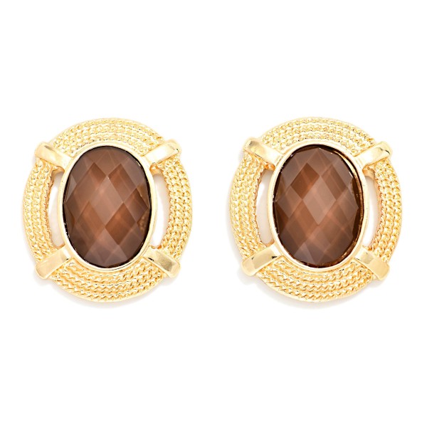 Oval Stone Statement Stud Earrings featuring a faceted oval cabochon set in a textured round metal frame with notched detailing. The decorative border adds vintage charm while the stone delivers rich, polished shine. Lightweight post backs make them comfortable from morning meetings through evening plans. Framed stone studs are a standout fall look and an easy upsell for customers building a curated earring wardrobe.